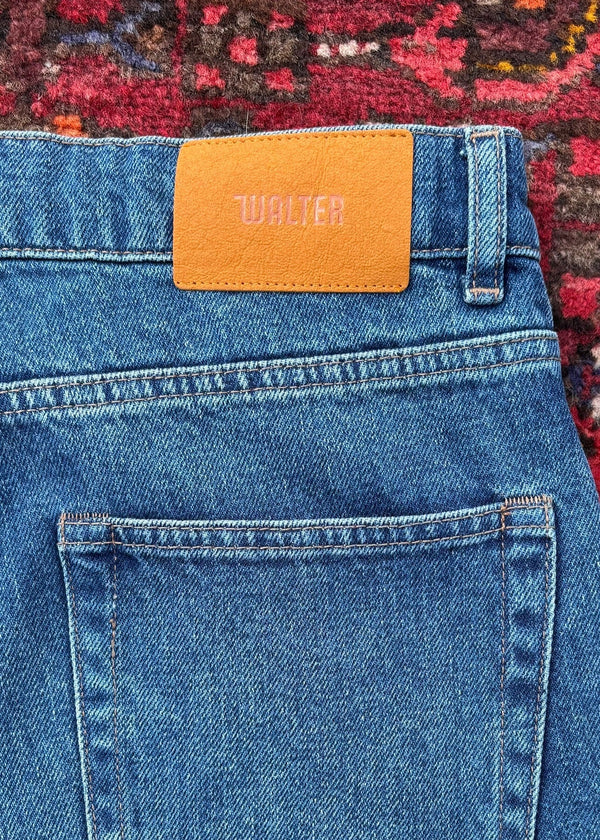 Close-up of blue jeans with a brand label on a patterned rug