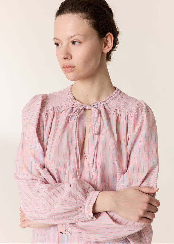 Woman wearing a pink blouse against a plain background