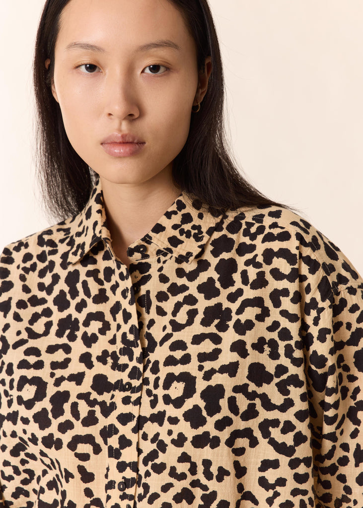 Person wearing a leopard print shirt against a plain background