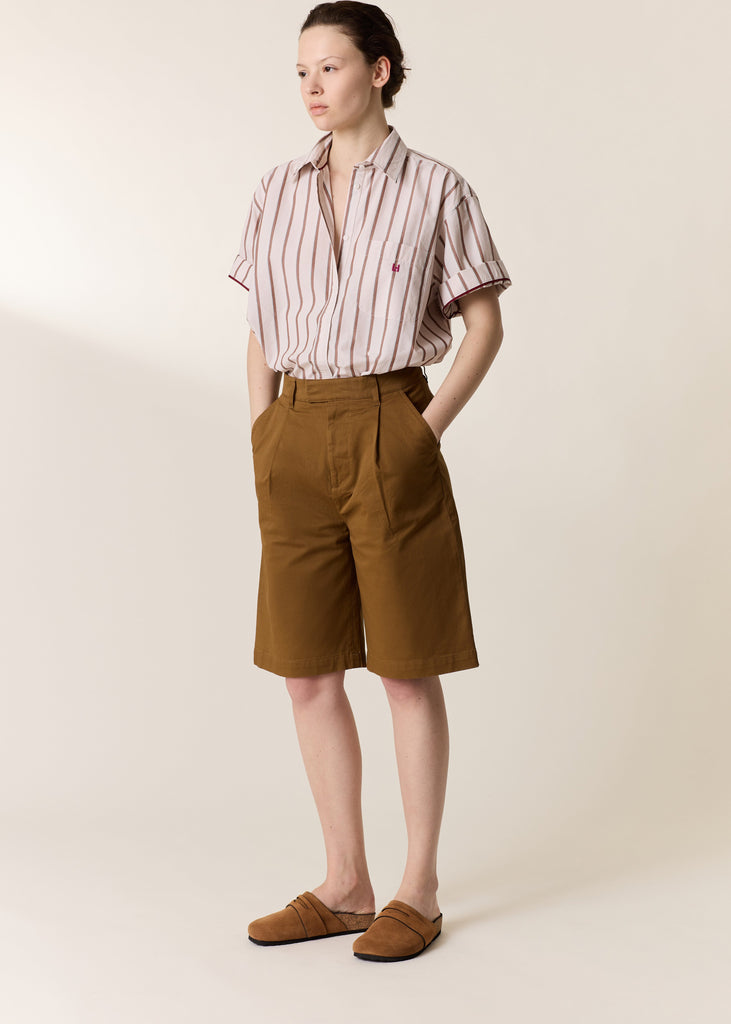 Person wearing a striped shirt and brown shorts on a plain background
