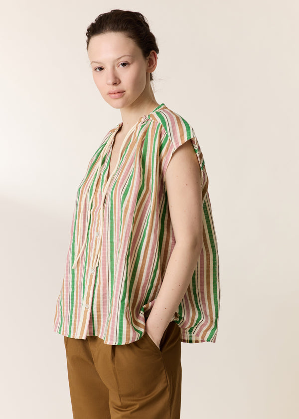 Woman wearing a sleeveless striped shirt against a plain background