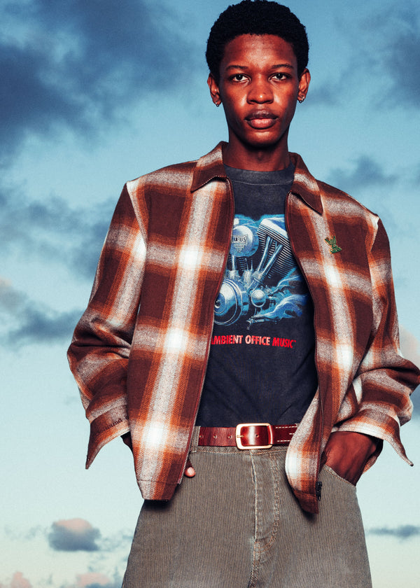Person wearing a plaid shirt over a graphic t-shirt with a blue sky background