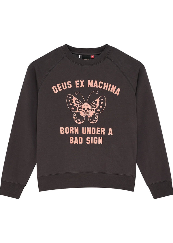 A dark brown crewneck sweatshirt with a pink graphic on the front featuring a butterfly with a skull in the center, and the text 'DEUS EX MACHINA' and 'BORN UNDER A BAD SIGN'.