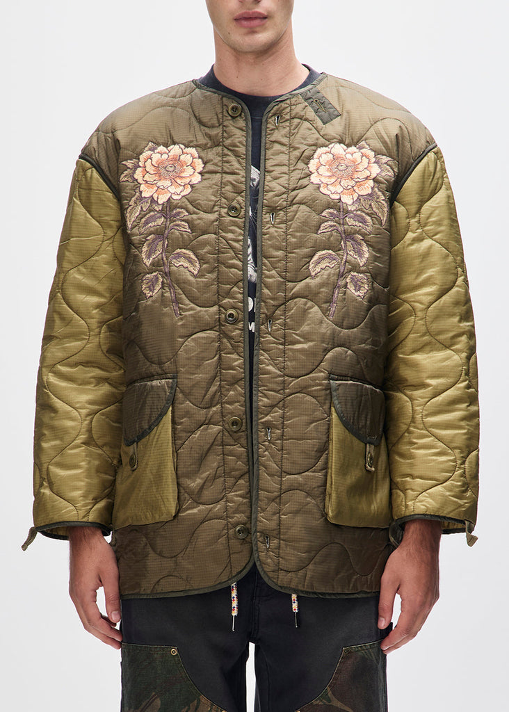 Green quilted jacket with floral embroidery on a white background