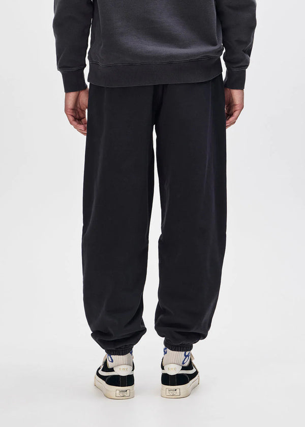 Person wearing a black tracksuit with white sneakers on a white background