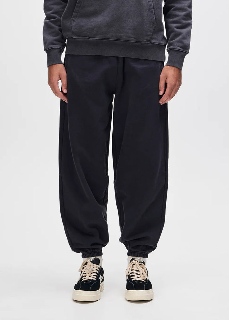 Person wearing black sweatpants and a dark hoodie on a white background