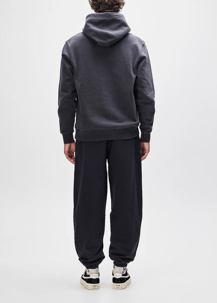 Person wearing a dark gray hoodie and black pants on a white background