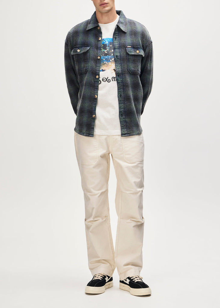 Person wearing a denim jacket, graphic t-shirt, and beige pants on a white background