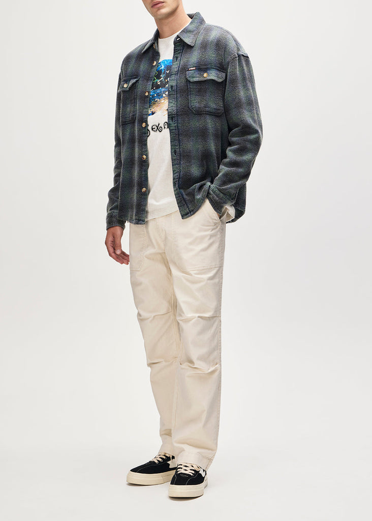 Person wearing a denim jacket, graphic t-shirt, and beige pants on a white background