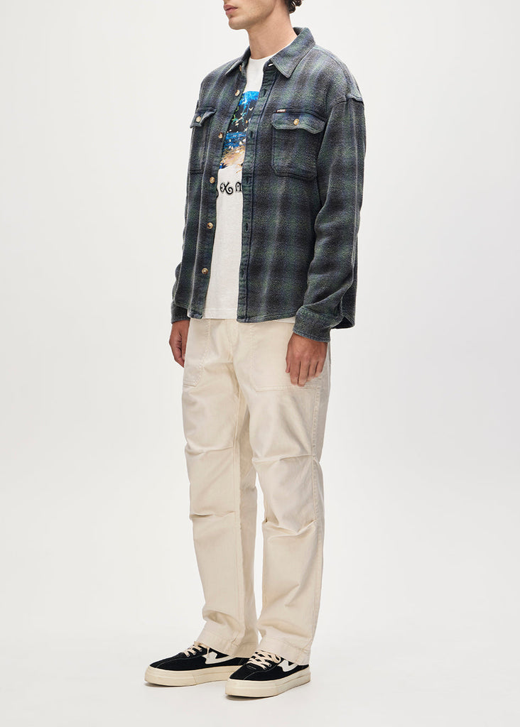 Person wearing a denim jacket, graphic t-shirt, and beige pants on a white background