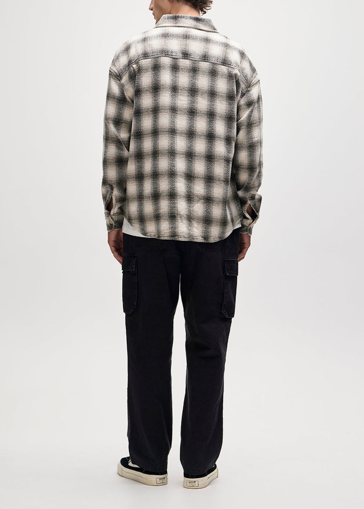 Person wearing a plaid shirt and black pants on a white background
