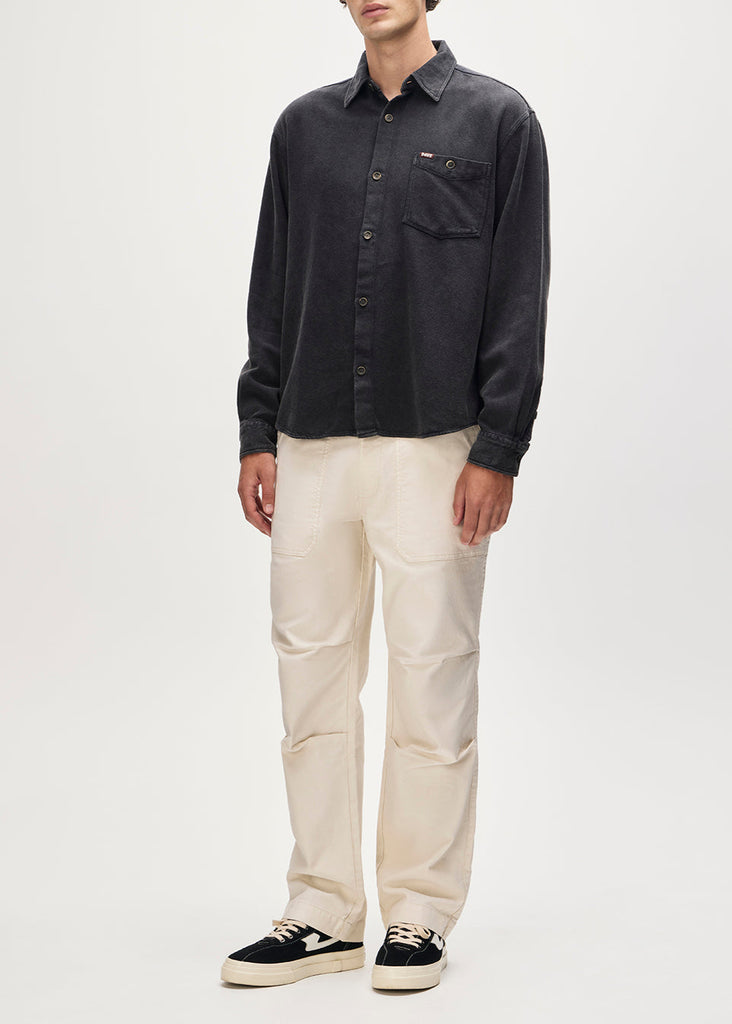 Person wearing a dark button-up shirt and light-colored pants on a white background
