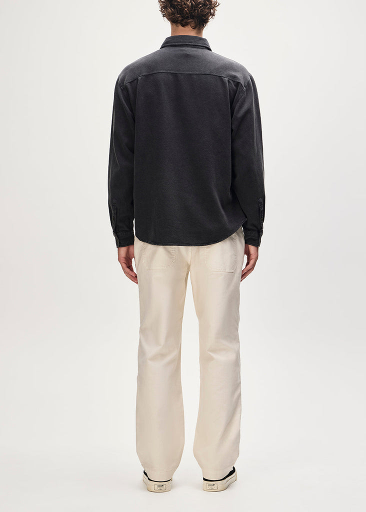 Person wearing a black shirt and beige pants on a white background