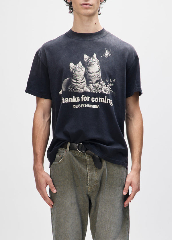 Person wearing a black t-shirt with cat graphic and text on a plain background