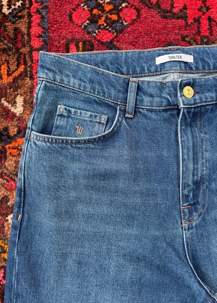 Blue jeans with a brand label on a patterned rug