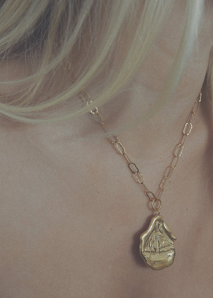 Gold necklace with a pendant on a person's neck