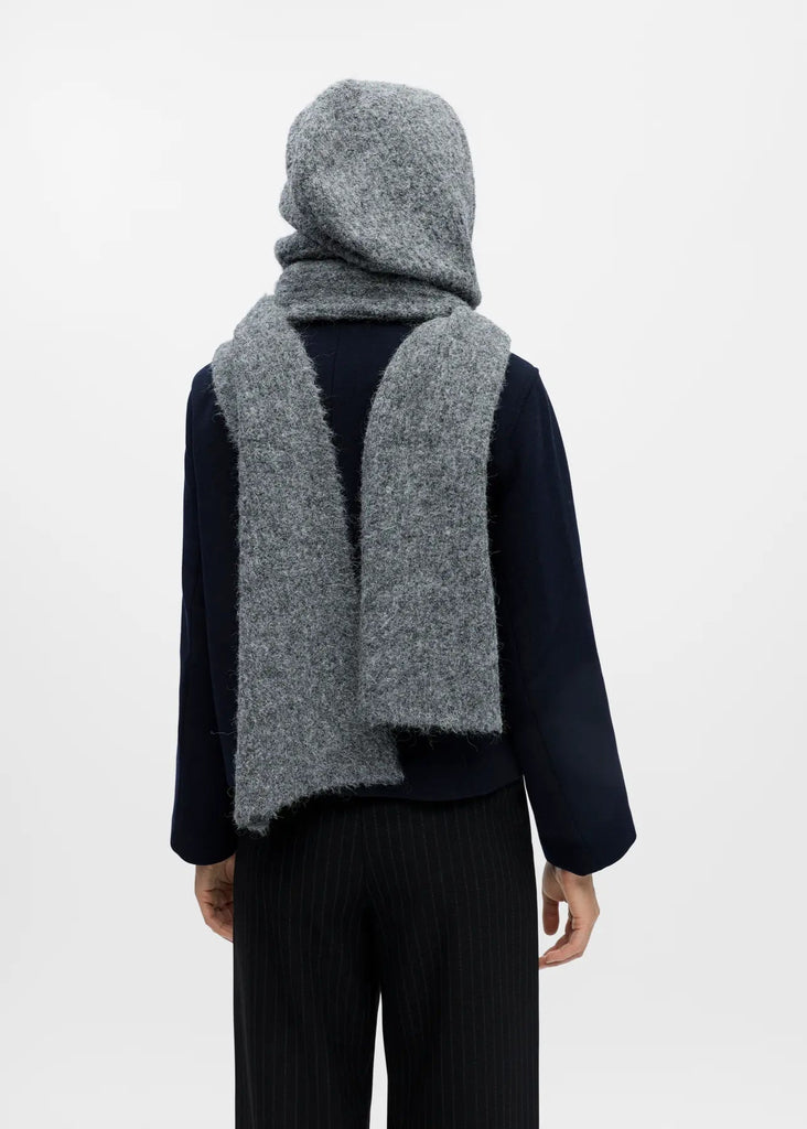 Person wearing a gray knitted scarf and hood on a white background