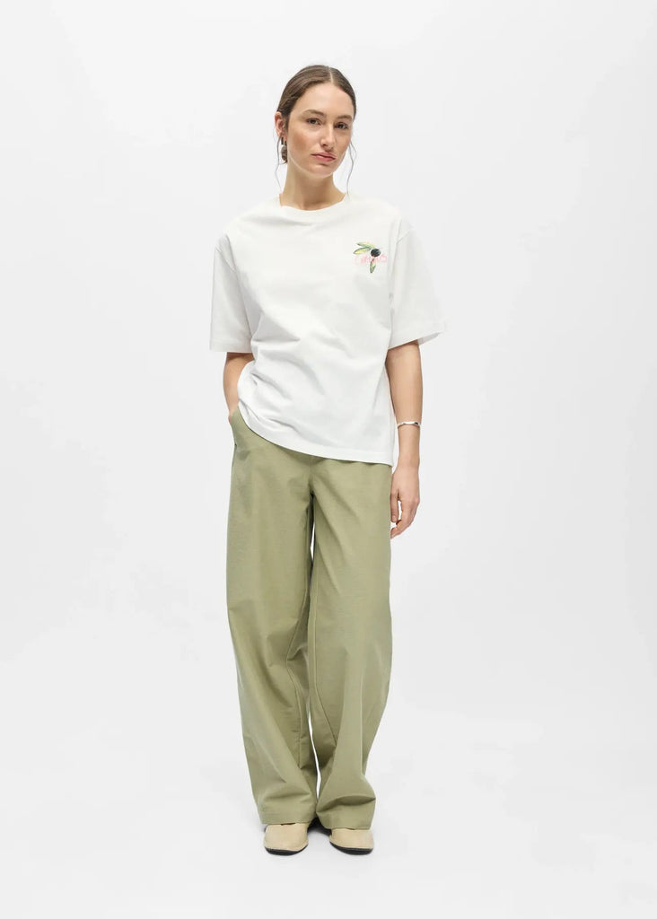 Person wearing a white t-shirt and light green pants on a white background