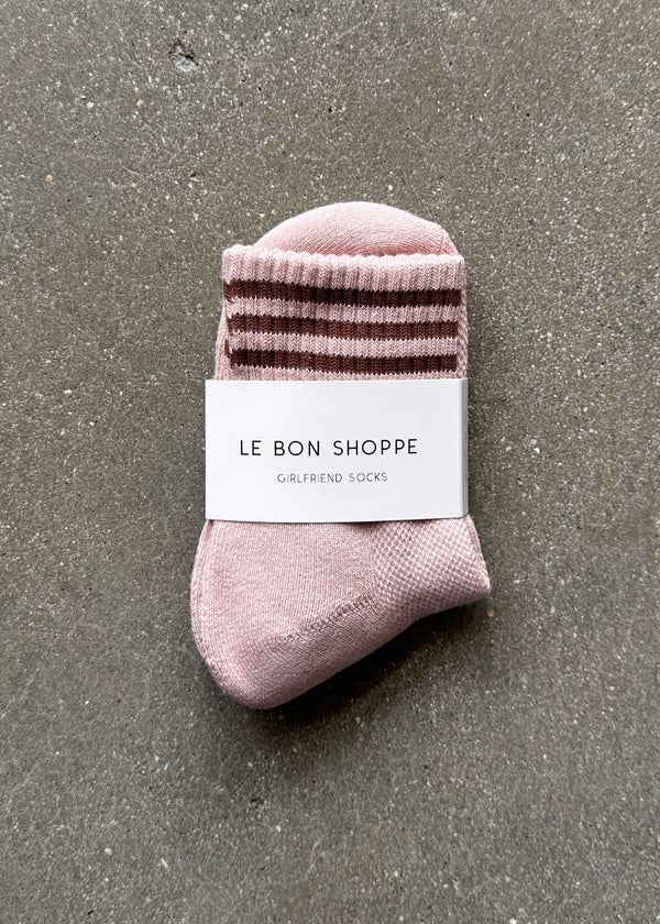Pink sock with brown stripes and a label on a gray surface