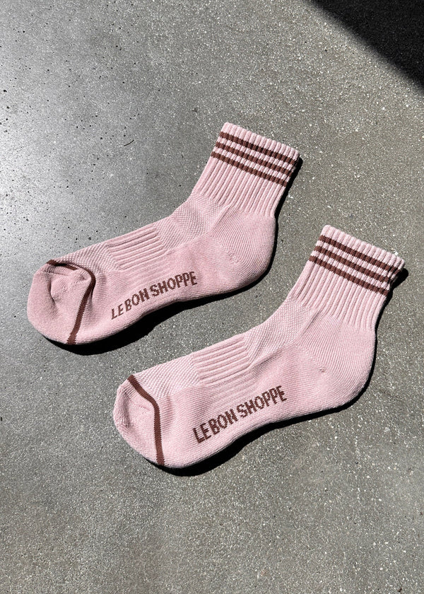 Pair of pink socks with striped cuffs on a gray surface