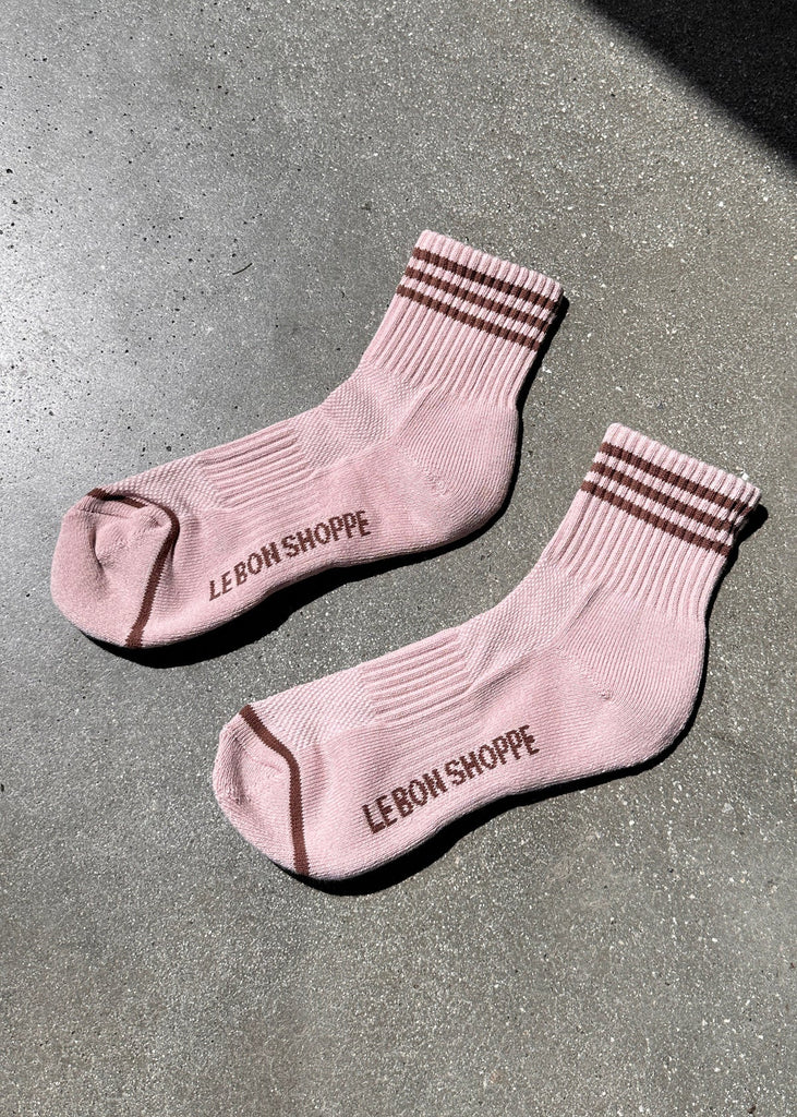 Pair of pink socks with striped cuffs on a gray surface