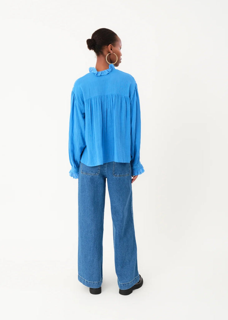 Person wearing a blue blouse and jeans on a white background
