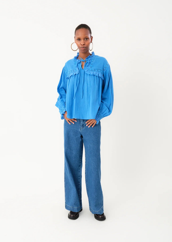 Person wearing a blue blouse and jeans on a white background