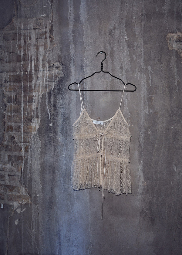 Lace top on a hanger against a textured wall