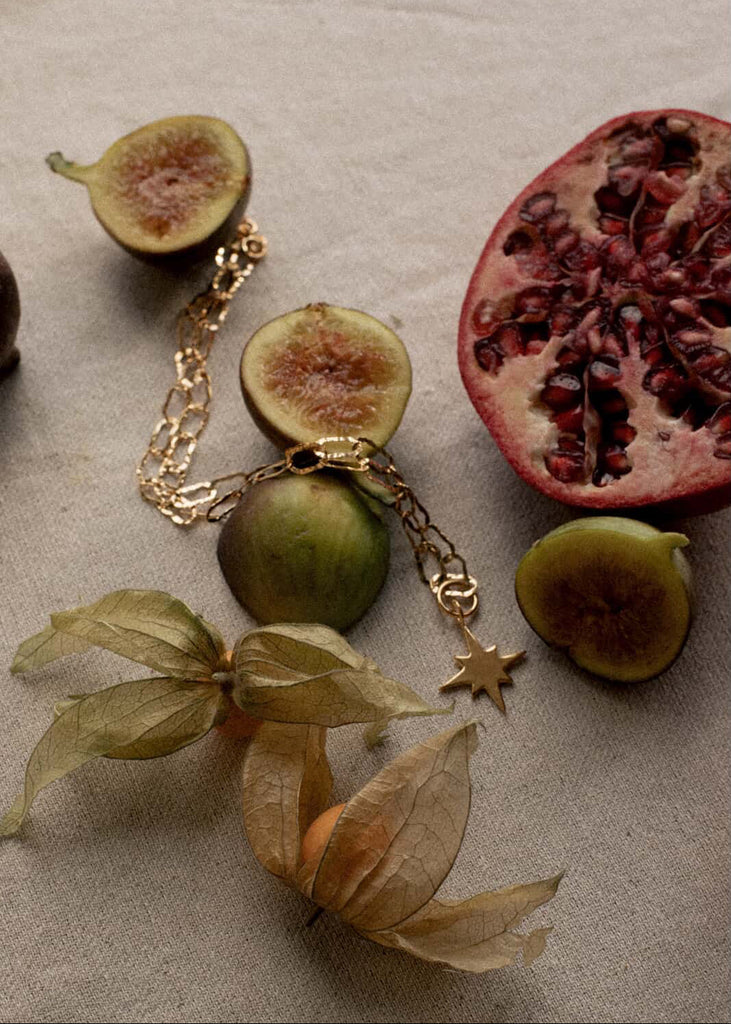 Gold bracelet with fruit charms on a textured surface