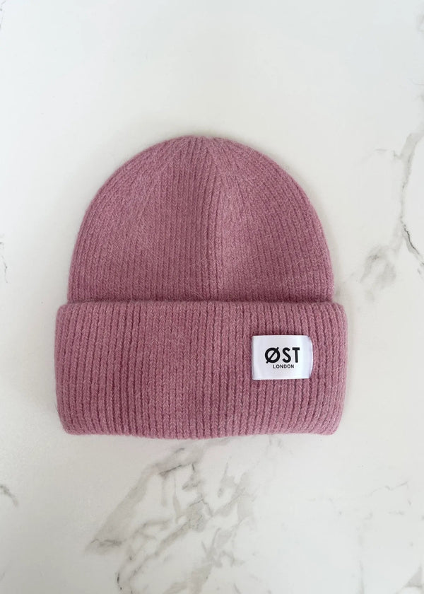 Pink beanie with a logo on a marble surface