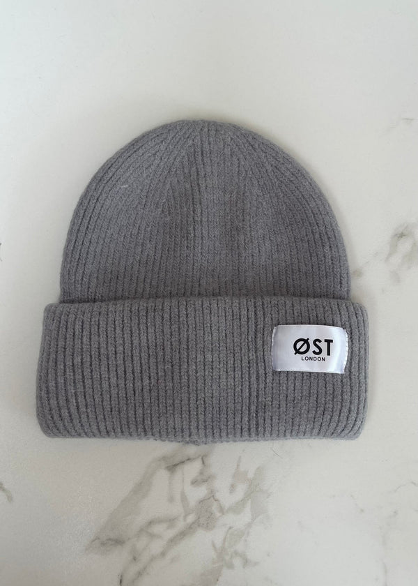 Gray knit beanie with a white label on a light marble background