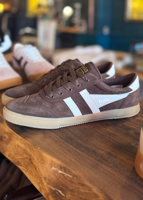 Brown sneakers with white stripes on a wooden surface