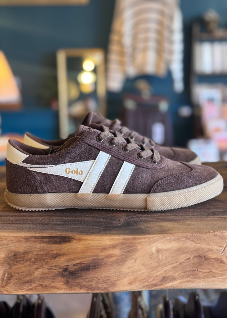 Brown sneakers with white stripes on a wooden surface, blurred background