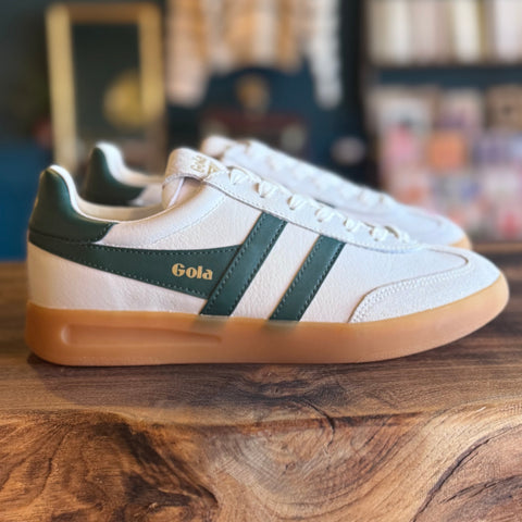 White sneakers with green accents on a wooden surface