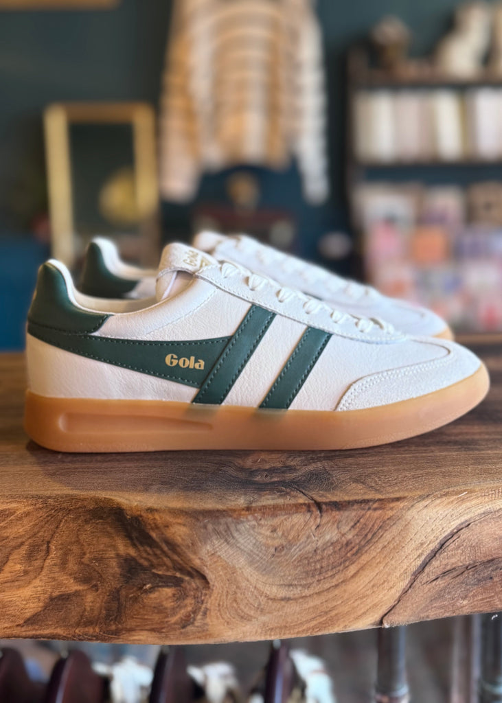 White sneakers with green accents on a wooden surface