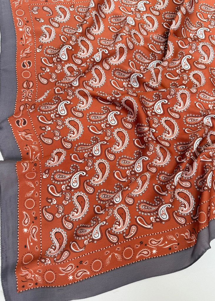 Orange fabric with white paisley pattern on a gray background