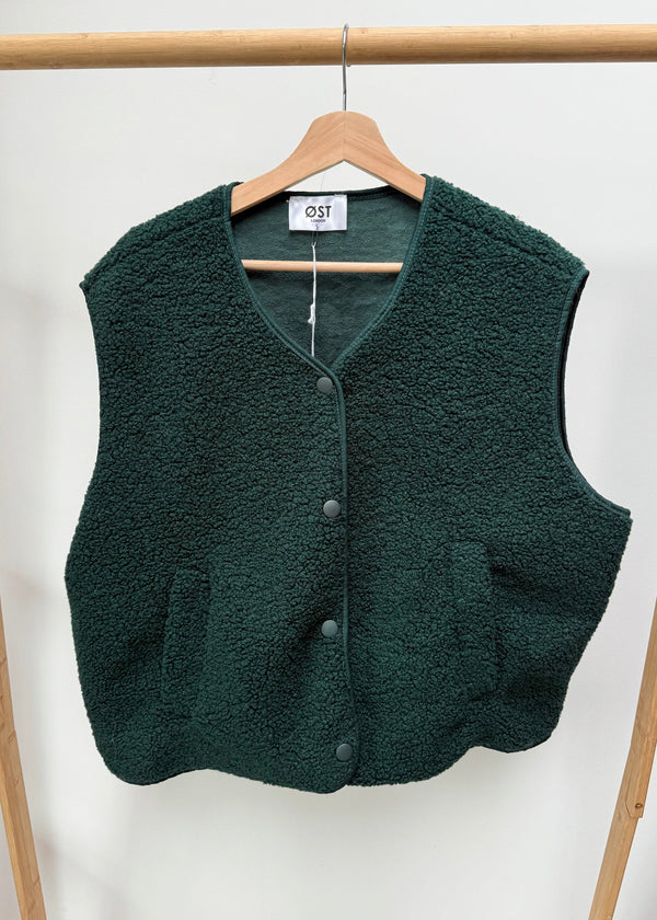 Green fleece vest on a hanger against a white background