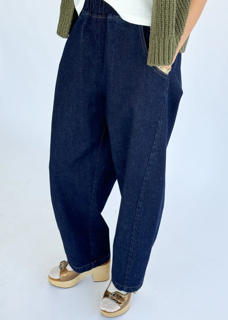 Person wearing blue jeans and gold sandals on a white background