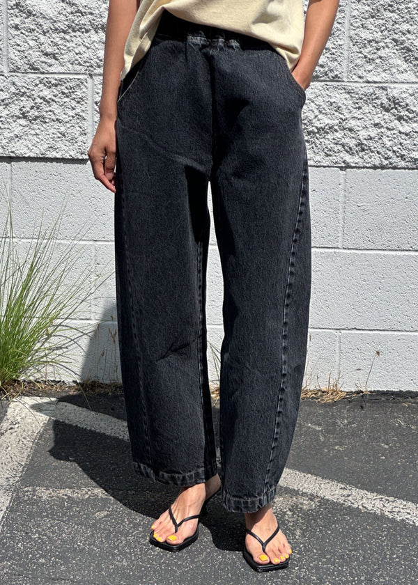 Person wearing black pants standing against a gray brick wall.