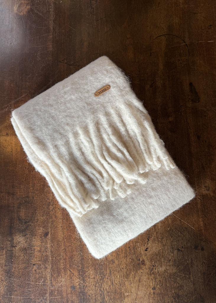 Beige scarf with fringes on a wooden surface