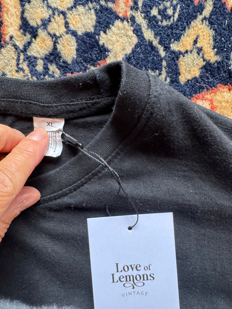 Black shirt with a 'Love of Lemons Vintage' tag on a patterned rug