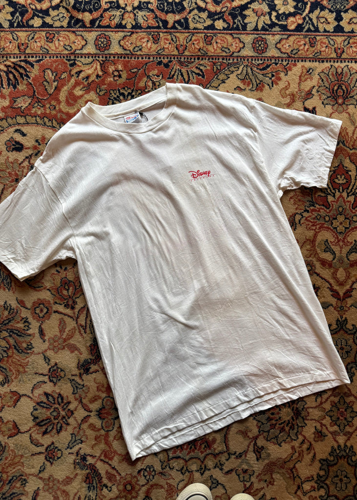 White t-shirt with a red logo on a patterned rug