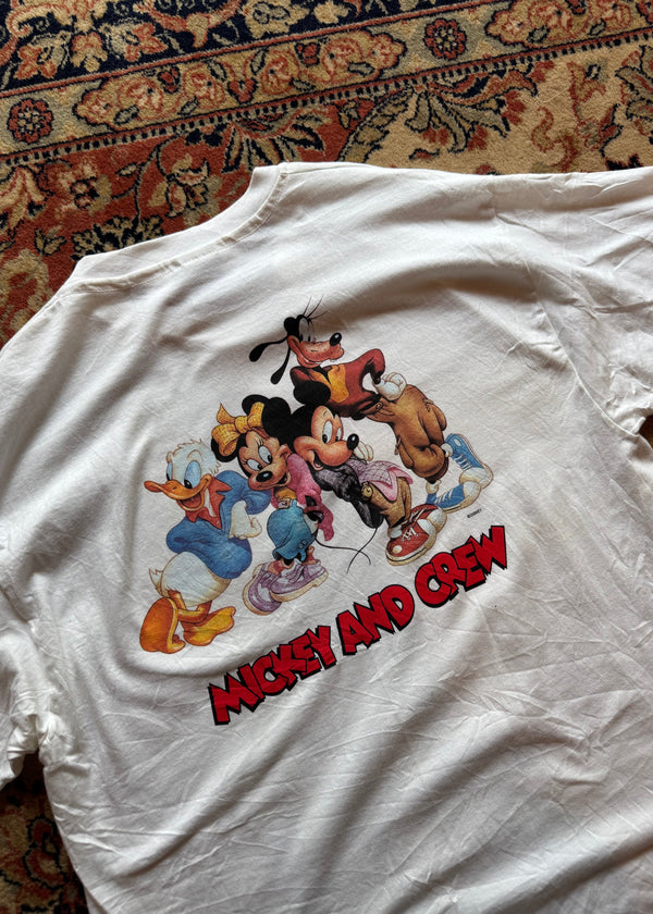 White t-shirt with cartoon characters and 'Mad Amigos' text on a patterned surface