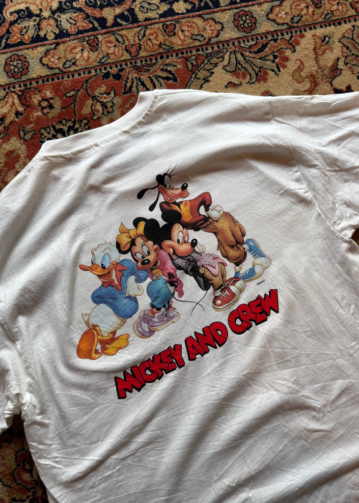 White t-shirt with cartoon characters and 'Mad Amigos' text on a patterned surface