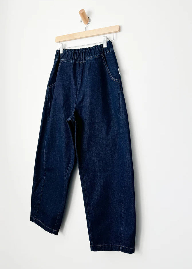 Blue jeans hanging on a wooden hanger against a white background