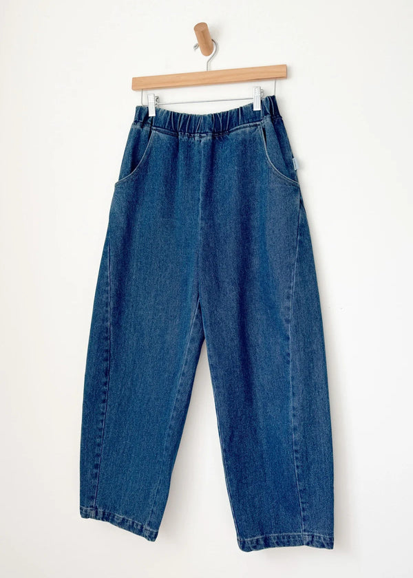 Blue jeans hanging on a wooden hanger against a white background