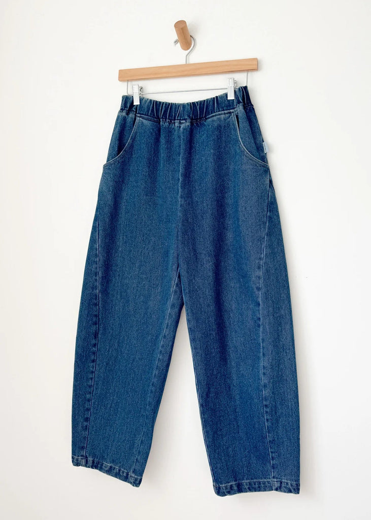 Blue jeans hanging on a wooden hanger against a white background