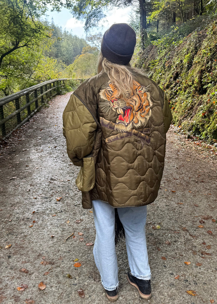 Person wearing a patterned jacket walking on a path with trees in the background