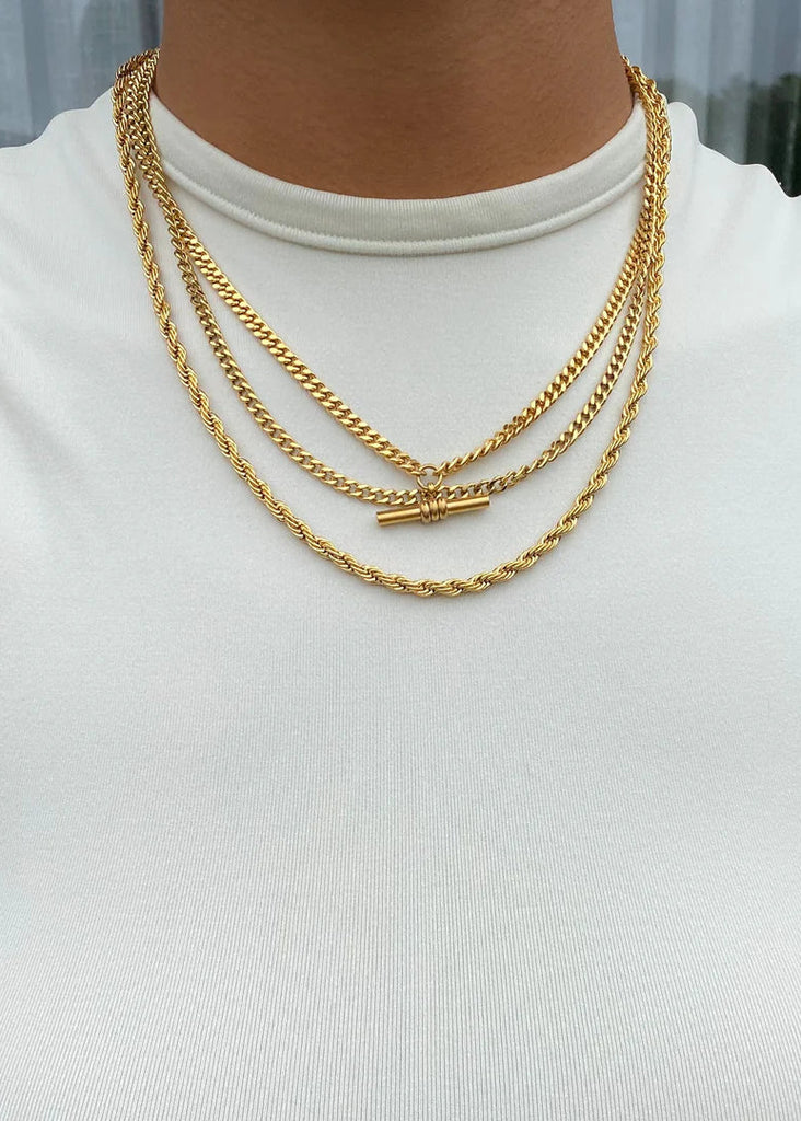 Gold chain necklace on a person wearing a white top with a blurred background