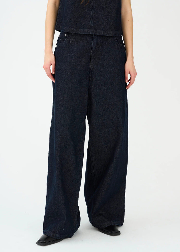 Person wearing dark blue wide-leg jeans on a white background